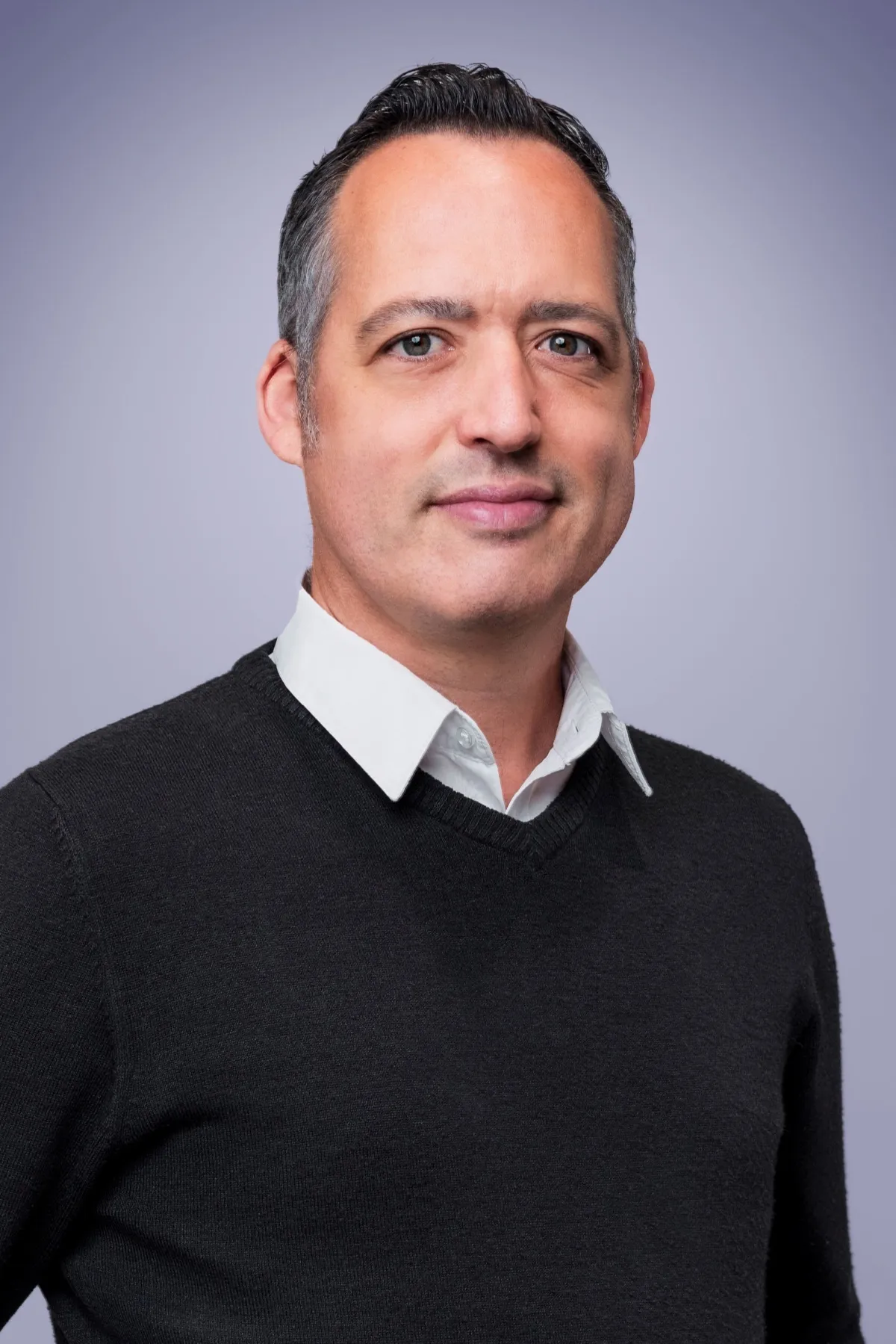 Martin O'Connell, Head of Marketing at Houss Rentals, in a dark jumper over a white collared shirt against a grey-purple background