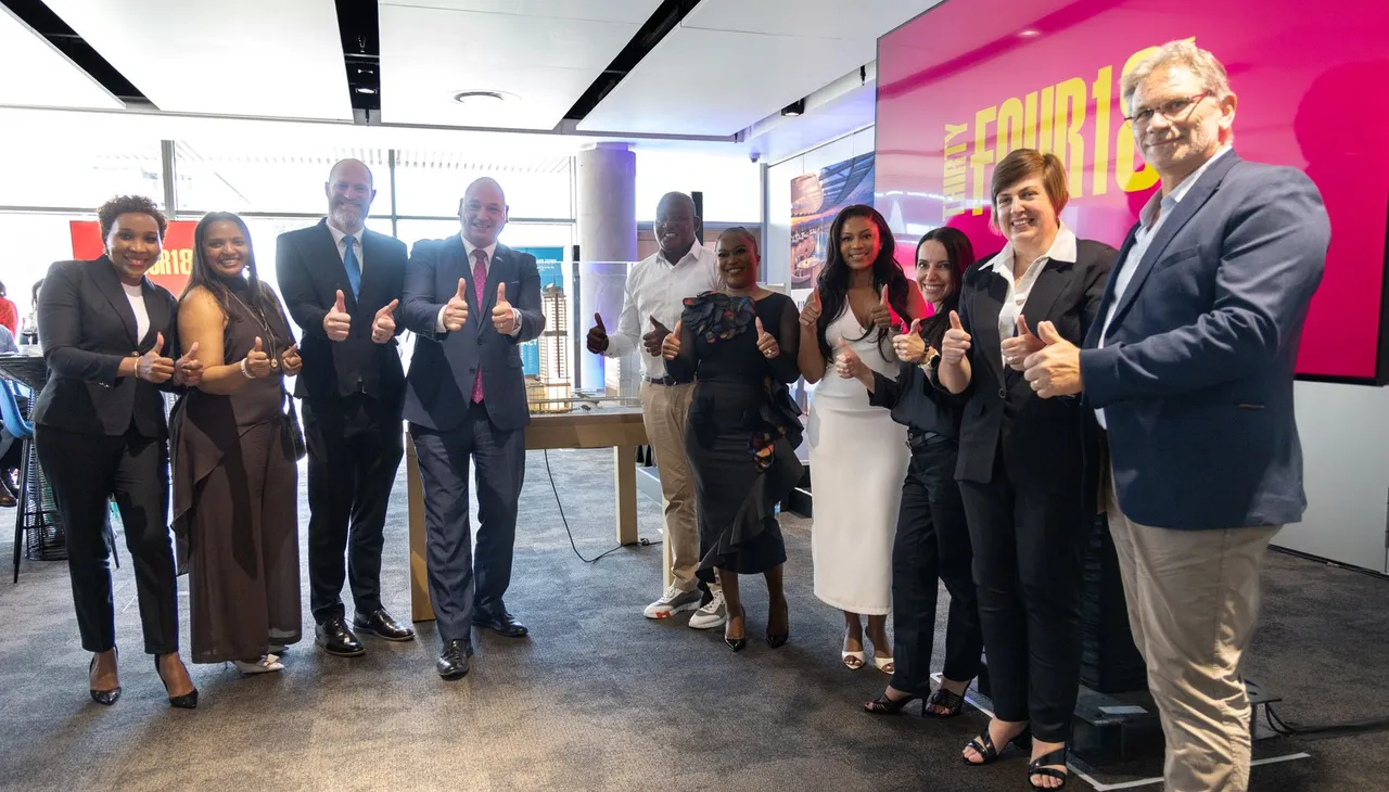 Eleven guests give a thumbs-up beside a scale model of the tower, in front of a pink screen showing the ThirtyFour18 logo