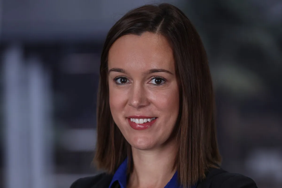 Lize Thiart, Transactor in Real Estate Investment Banking at RMB, in a black blazer and blue blouse with her arms crossed