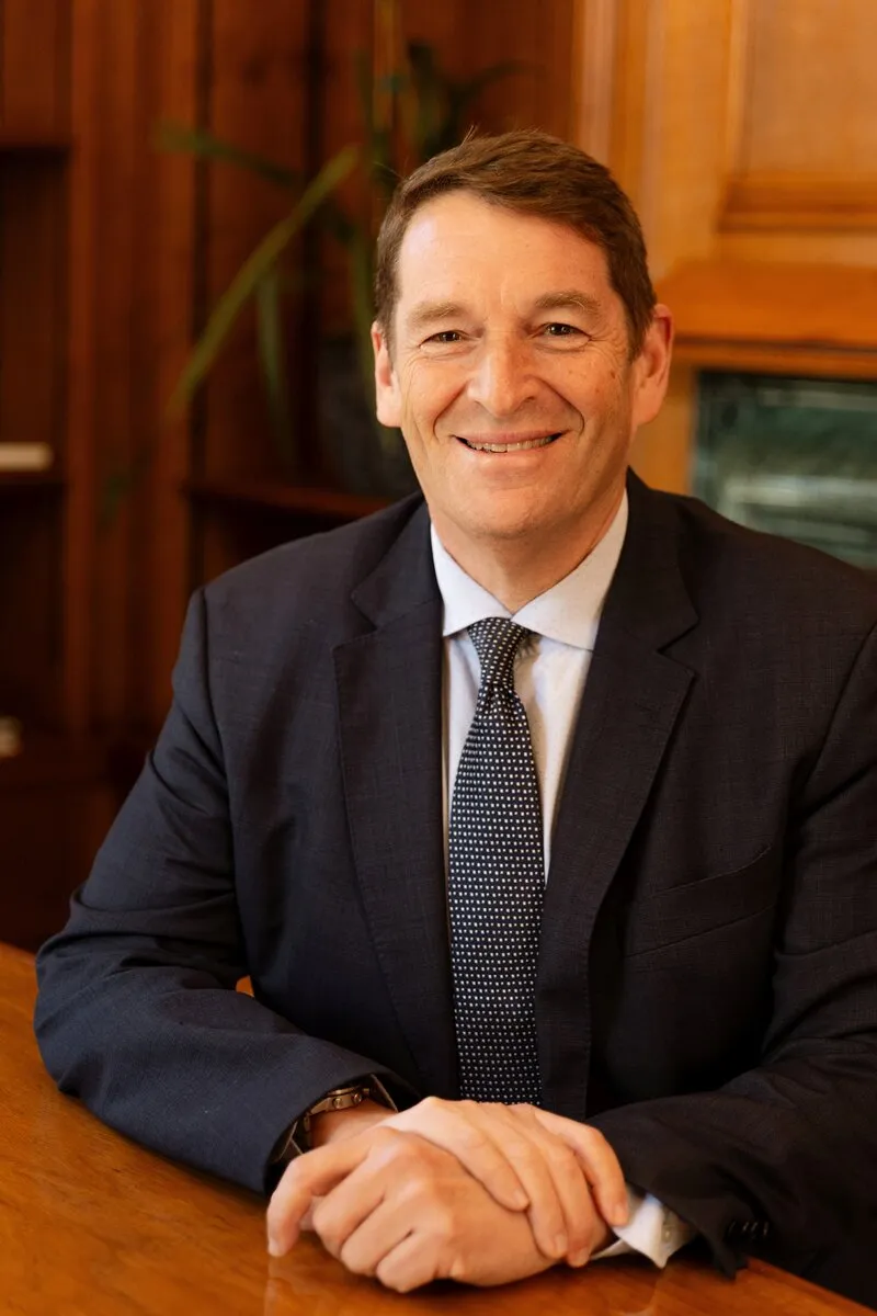 Dr Andrew Golding, chief executive of the Pam Golding Property Group, smiling in a dark suit and tie, seated at a wooden table with his hands folded