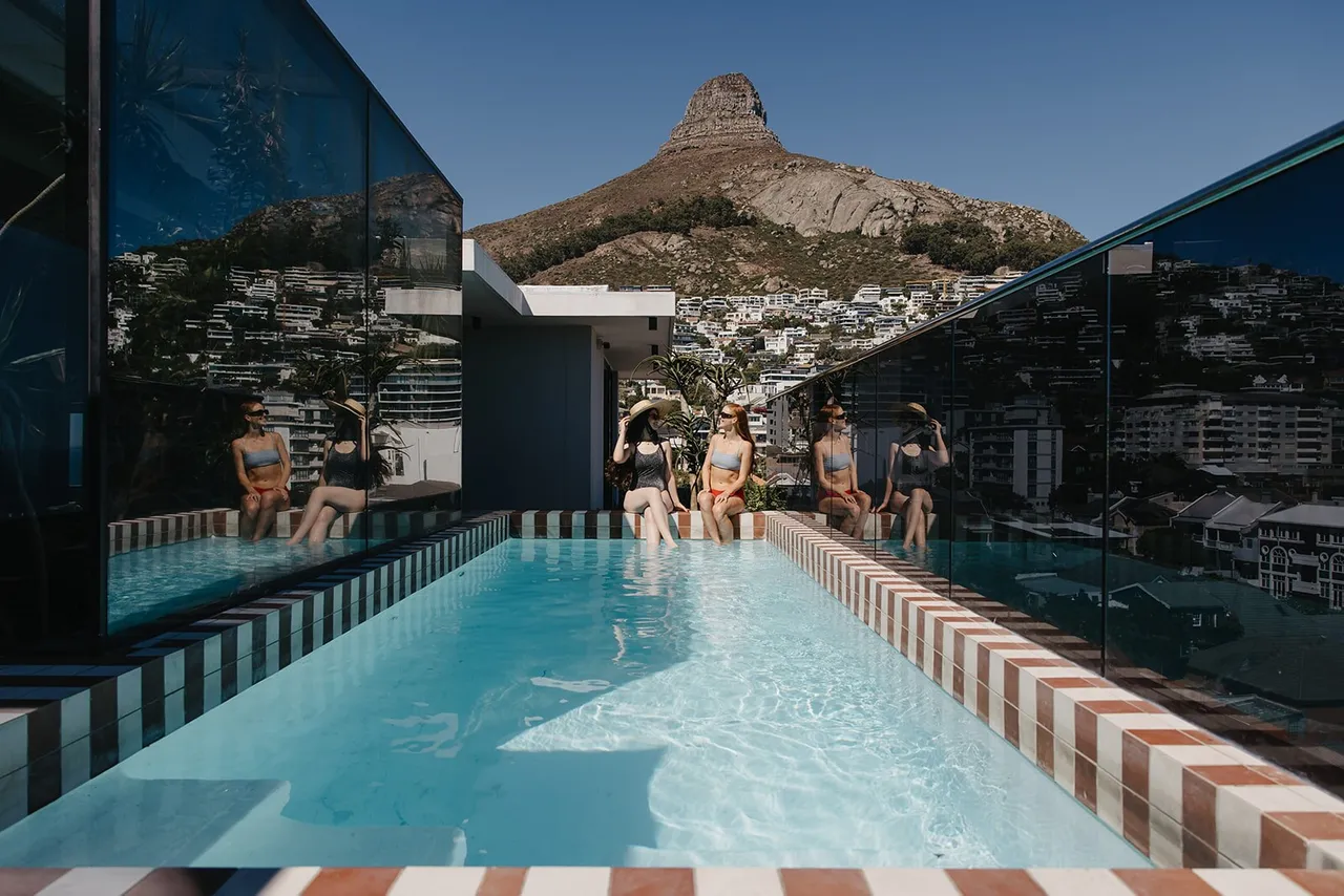 Guests relaxing beside the rooftop pool at Latitude in Cape Town, with Lion’s Head behind