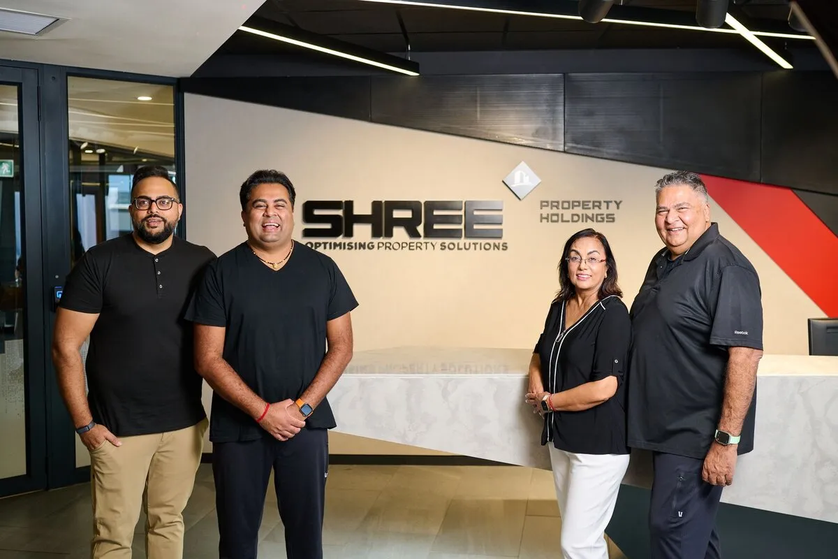Four members of the Shree Property Holdings team, smiling in the company's reception in front of the Shree Property Holdings logo