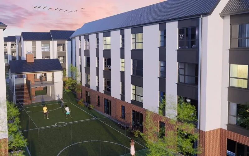 Artist's impression of a four-storey affordable housing development with a sports court in the courtyard where children play, under a pink evening sky