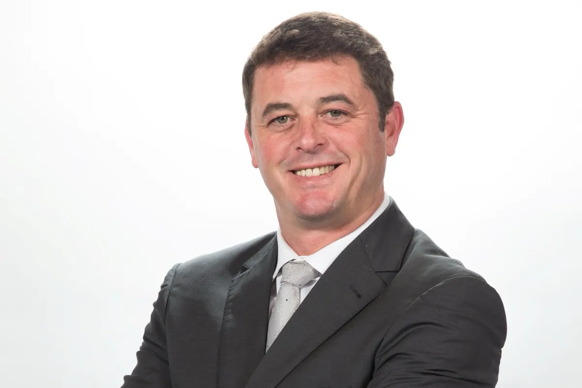Engelbert Binedell, Chief Operating Officer at Growthpoint Properties, smiling with his arms crossed in a dark suit