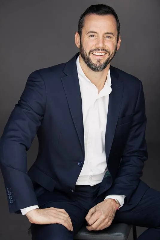 John Jack, CEO of Galetti Corporate Real Estate, seated in a navy suit and white open-collar shirt