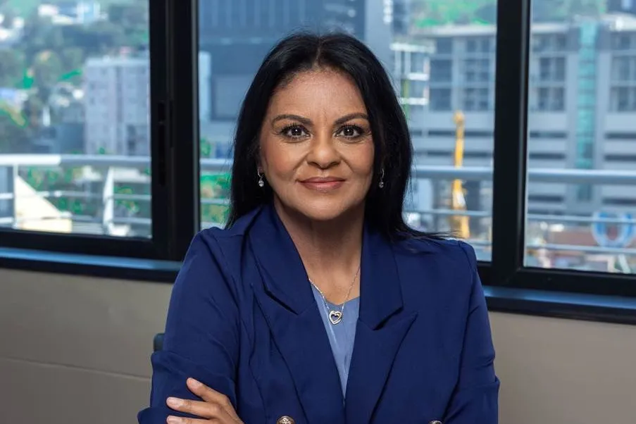 Jackie Smith, CEO of Buyer’s Trust, in a navy blazer with her arms crossed at a table in front of a window