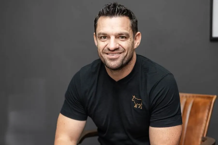 Grant Smee, CEO of Only Realty Group, smiling in a black T-shirt, seated in front of a dark wall