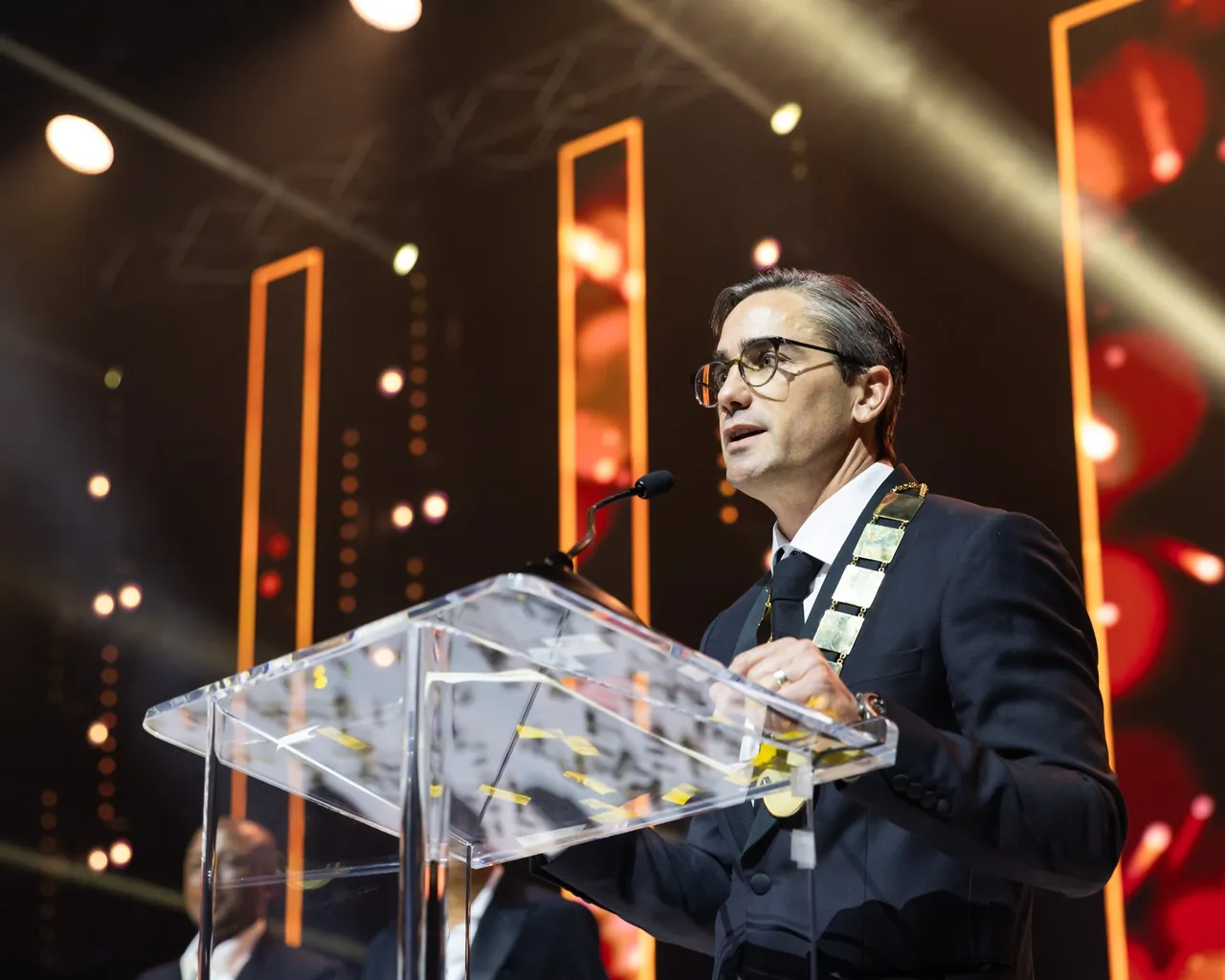 Steven Brown, new SAPOA president, speaking at a clear lectern in his presidential chain against orange-lit stage screens