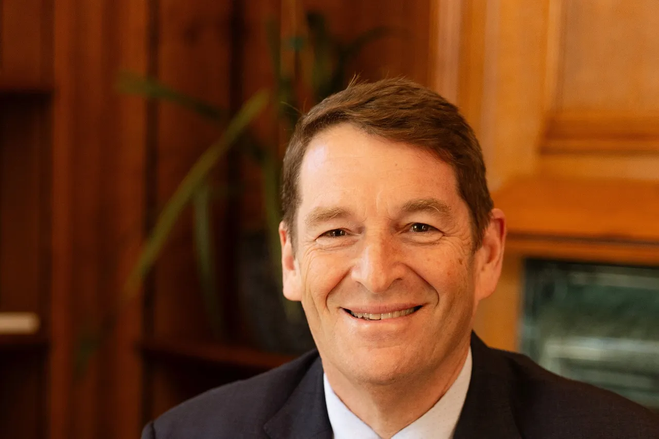 Dr Andrew Golding, chief executive of Pam Golding Properties, smiling in a dark suit and patterned tie in a wood-panelled office