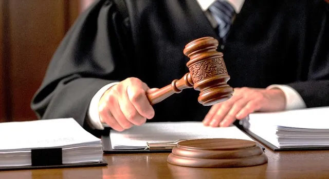A judge brings down a gavel beside bound court papers